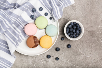 macaroons of different colors in a plate on a gray cement background. top view