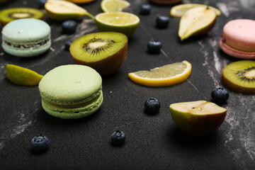 macaroons of different colors with fruits on black marble