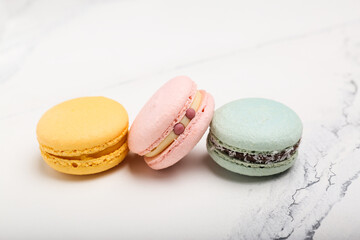 three colored macaroons on white marble