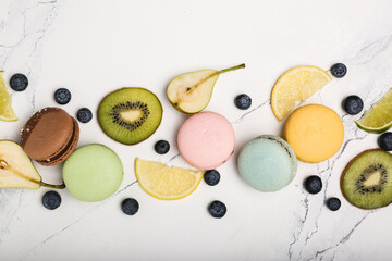 macaroons of different colors with different fruits on white marble. top view