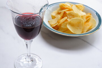 赤ワインのグラスと、ボウルに盛ったポテトチップス