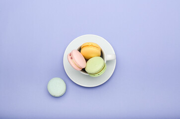 colorful macaroons in a cup on a purple background. Top view