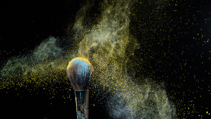 Shaking off yellow powder from a brush on a black background. 