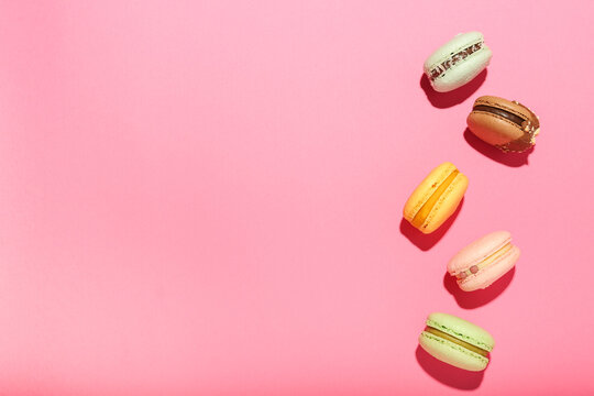 multicolored macaroons on a pink background. Top view, space for text