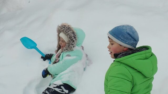 A family with children walks in the winter in the forest. Boy and girl on a walk in the forest or park. play, throw snowballs, wallow in the snow, snow angel. Holidays for Christmas, New Year.