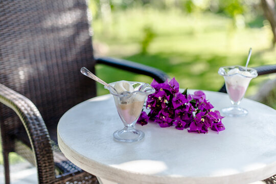Ice creams and purple flower (begonvil) on the table of an outdoor restaurant 