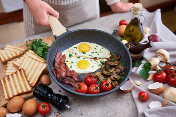 Fried eggs and bacon on a pan at domestic kitchen