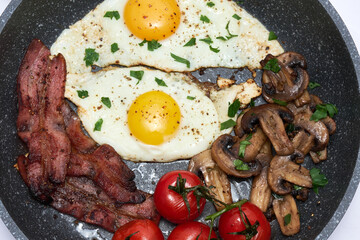 Fried eggs and bacon on a frying pan isolated on white background