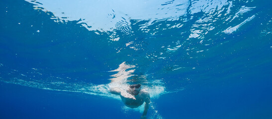 Fototapeta na wymiar Boy swims freestyle in the open ocean.