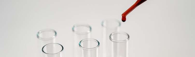 Close-up of a laboratory assistant dripping blood from a pipette into a test tube on a white background. 