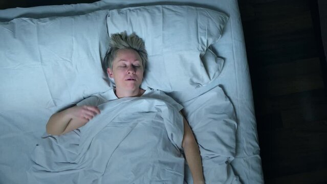 Sleeping man snores in his sleep in bed, top view.