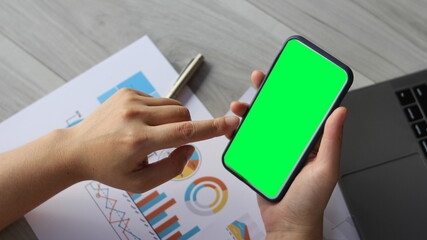 Using smartphone with a vertical green screen,Close up of female hands holding modern smartphone with green mock up screen.