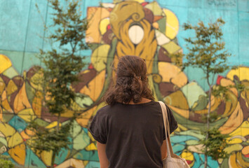 Young woman from behind looking at wall art at Porto, Portugal. Summer time traveling. 