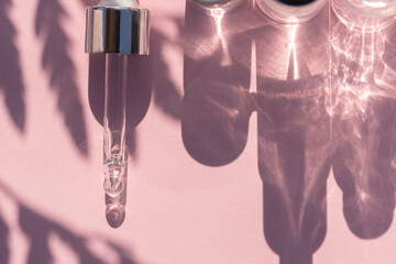 Pipette dropper with face serum and bottle shadows on a pink background