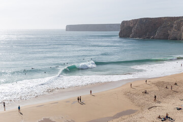 People at the beach watching surfers at Atlantic Ocean , Portugal
