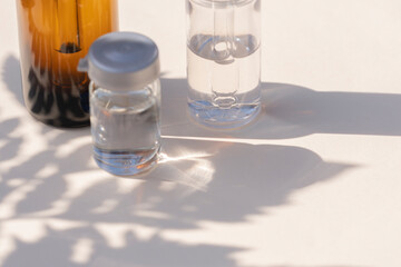 Face serum bottles with shadows and fern leaf shadow on a beige background