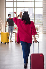 Woman raise hand to say hi to friends at airport terminal