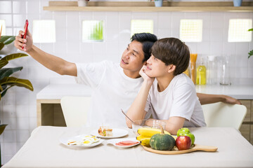 Young LGBT Asian gay couple selfie or video call at breakfast