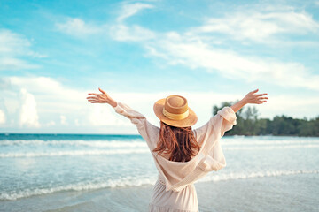 Summer beach vacation concept, Young woman with hat relaxing with her arms raised to her head...