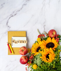 notepad, pencils, book, bright bouquet with sunflowers, apples on marble background. august month...
