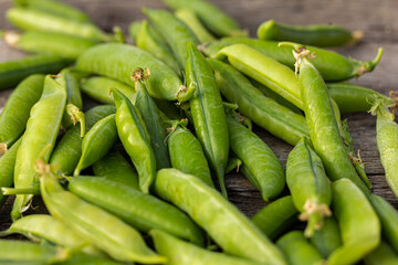 Green garden pea pods on dark wooden background.  straight-out-of-the garden peas. Macro, stock photo