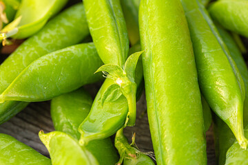 Green garden pea pods on dark wooden background.  straight-out-of-the garden peas. Macro, stock photo