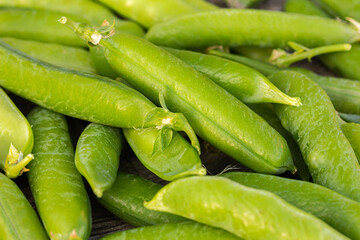 Green garden pea pods on dark wooden background.  straight-out-of-the garden peas. Macro, stock photo