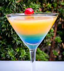 Blue-orange layered cocktail in a martini glass