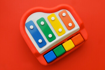 Top view of little cute colorful piano toy isolated on red background

