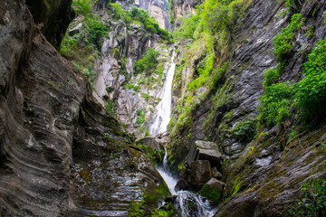 Beautiful and spectacular natural waterfall falling through rocky mountains in manali, Himachal pradesh, India. A perfect morning landscape of lush green and rocky mountains and powerful waterfall.