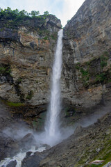 Mighty Sissu waterfall falling with all the force in Lahaul valley, Himachal Pradesh. Waterfall falling from rocky mountain. Waterfall surrounded by Green mountains and clear skies on a pleasant day.