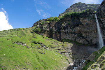 Mighty Sissu waterfall falling with all the force in Lahaul valley, Himachal Pradesh. Waterfall falling from rocky mountain. Waterfall surrounded by Green mountains and clear skies on a pleasant day.