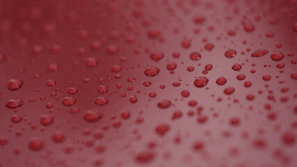 closeup shot of raindrops on red car with hydrophobic coating
