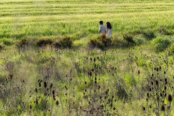 Obraz na płótnie Canvas Couple walking between green fields 