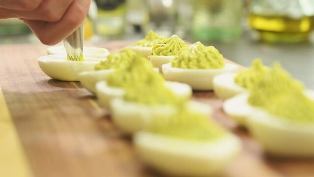 Preparing deviled eggs with avocado and basil.
