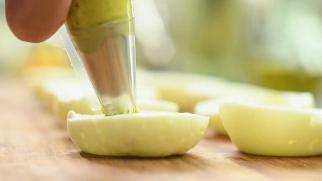 Preparing deviled eggs with avocado and basil.
