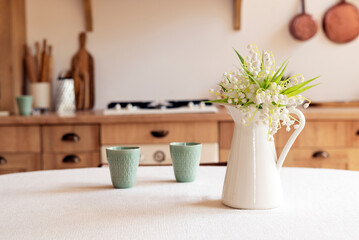 Bouquet of spring flowers in a vase on the kitchen table. Light scandinavian style. Mothers Day. March 8, International Women's Day