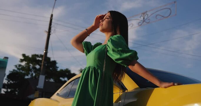Beautiful woman posing near a yellow luxury car, slow motion