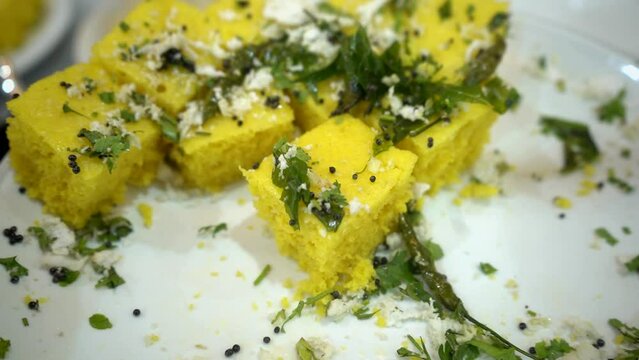 Extreme close up video of Gujarati Yellow Dhokla made using Chana Dal, served with Green chutney.