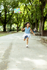 Little Asian girl running happily with a kite in the park