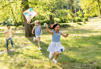 Obraz premium Little Asian girl running happily with a kite in the park