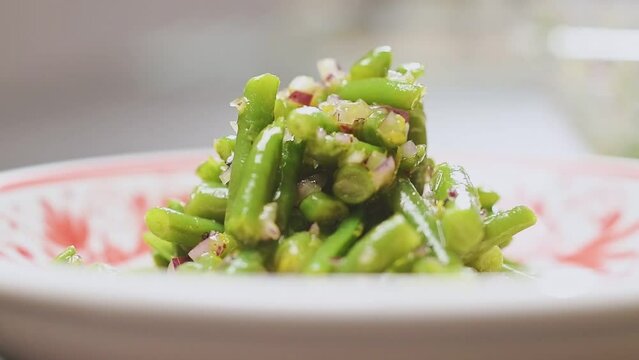 Chef serves freshly prepared green bean salad.
