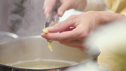 Chef cooking and testing italian pasta in the kitchen.
