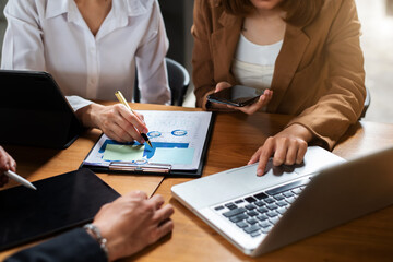 Coworking team meeting.Group of young businessmans working with new startup project while typing on laptop, tablet and writing on notebook