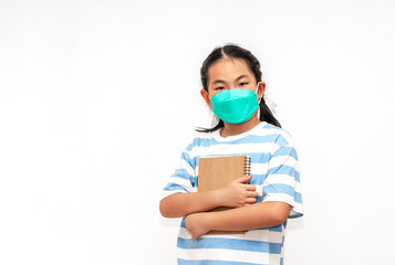 Portrait student Asian child girl holding a book, wearing face mask for protection in era of covid virus, isolated student child girl on white background, concept for back to school.