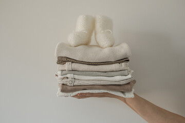 Aesthetic Scandinavian newborn baby clothes, socks stack in person's hand on white background....