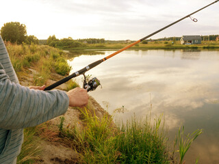 Fishing rod wheel closeup, man fishing on the lake