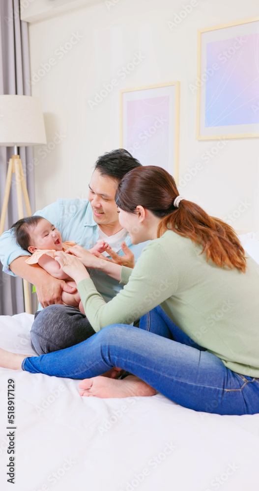 Wall mural Young parents play with baby