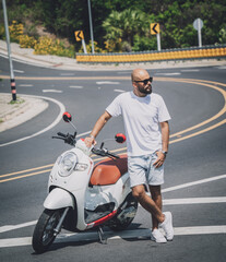 Fototapeta na wymiar Stylish young man with his motorbike on the road