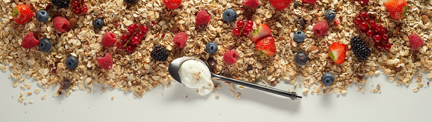 Spoon with yogurt on oat with berries on table